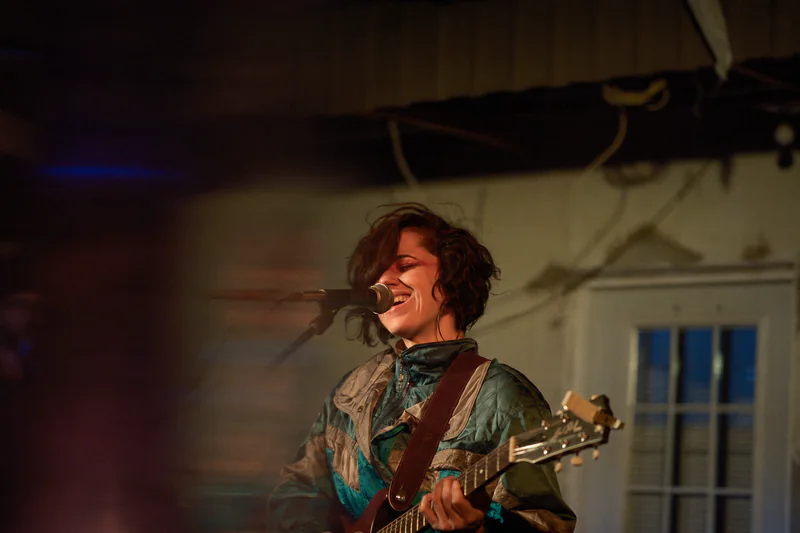 JER singing into the microphone while playing guitar live